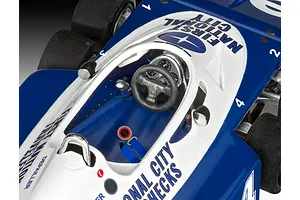 Close-up top-down view of the cockpit of a blue and white Tyrrell P34 Formula 1 model car, showing the steering wheel, dashboard, and seat harness.