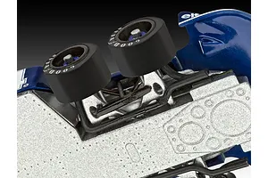 Close-up view of the front suspension and dual front wheels of a Tyrrell P34 Formula 1 model car, showing metallic chassis detail.