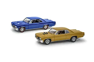 Two assembled 1/24 scale 1964 Pontiac GTO model cars, one in metallic blue and one in metallic gold, displayed against a white background.