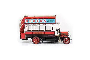 Side view of a completed OcCre 1/24 scale AEC B-Type London bus model, featuring red and white paint with Dewar's Whisky advertising signage.