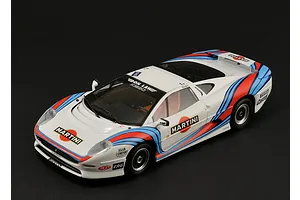 A high-angle studio shot of a 1/24 scale Jaguar XJ220 race car model with white, red, and blue Martini racing livery on a black background.