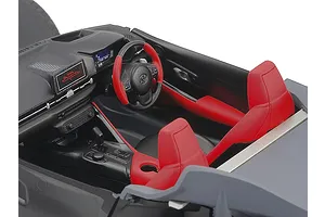 Close-up of the detailed interior of a 1/24 scale Tamiya Toyota GR Supra model kit, showing the dashboard, red and black bucket seats, and steering wheel.