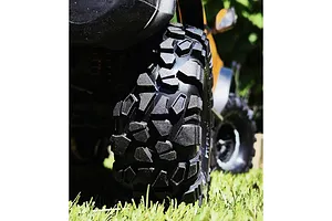 Close-up of a Louise 1.9 inch RC crawler tyre with aggressive tread pattern mounted on a black rim, positioned on green grass.