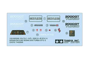 A decal sheet for a 1/24 scale Tamiya Nissan Skyline 2000 Turbo GT-E S model kit, featuring various badges, dashboard gauges, and text labels.