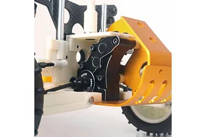 A close-up view of a black Yeah Racing aluminium gearbox case installed on an RC car chassis with a gold bumper.