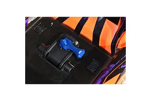 A blue aluminium body shell lock installed on an orange and black patterned RC car body shell.