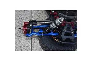Close-up of a blue aluminium RC suspension arm installed on a vehicle chassis, featuring red accents and a shock absorber.