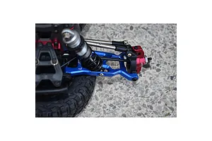 Close-up of a blue aluminium RC suspension arm installed on a vehicle chassis with red steering components and a black rubber tire.