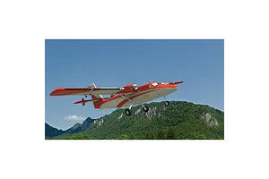 A digital simulation of a red and white twin-engine RC plane flying over a mountainous landscape in RealFlight Evolution.