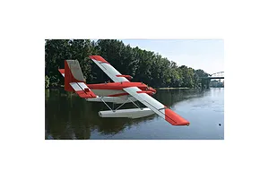 A digital rendering of a red and white de Havilland floatplane flying over a river in the RealFlight simulator.