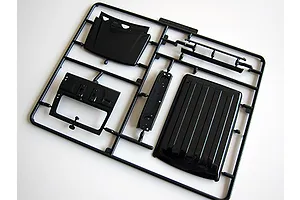 A black plastic sprue frame containing model car parts, including a roof panel and interior components, for a 1/24 scale Suzuki Jimny model kit.