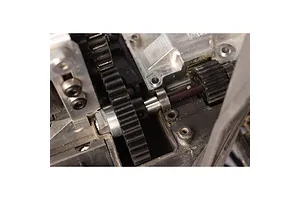 Close-up of a black metal spur gear installed in an RC car drivetrain assembly.