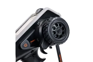 Close-up of the steering wheel and power button on a Spektrum DX Rugged RC transmitter, showing the textured rubber tire grip and orange power label.