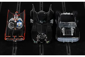 Three Scalextric 1/32 scale Batmobile slot cars from the Ultimate Collection set, displayed on a black slot car track.