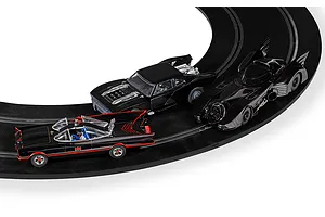Three Scalextric Batmobile slot cars racing on a curved black track, including the 1966 classic, the 1989 movie version, and a modern muscle car style Batmobile.
