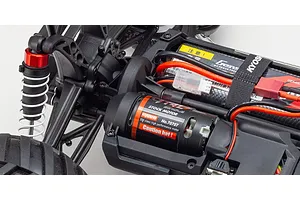 Close-up of the internal chassis of a Kyosho RC vehicle showing the 550 class brushed motor, battery pack, and suspension components.