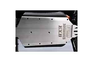 A close-up view of a GPM Racing stainless steel chassis skid plate installed on an RC vehicle, featuring laser-etched branding.