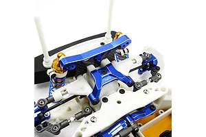 Close-up of a blue anodized aluminium upper arm mount installed on an RC car chassis with white plastic suspension components.