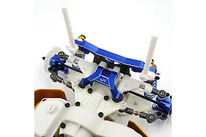 Close-up of a blue anodized aluminium upper arm mount installed on a white RC car chassis with carbon fiber and plastic components.