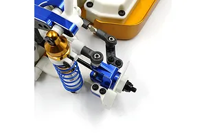 Close-up of a blue anodized aluminium RC steering hub carrier and linkage assembly installed on a white and gold RC chassis.