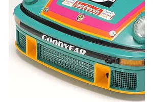 Close-up of the front bumper and hood of a Tamiya 1/24 scale Porsche 934 Turbo RSR Vaillant model car, featuring teal, orange, and pink racing livery.