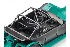 Close-up of the interior of a Tamiya 1/24 scale Porsche 934 model car, showing the black roll cage, bucket seat, dashboard, and teal chassis.