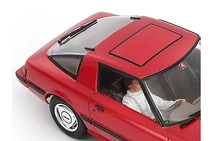 High-angle close-up of a red 1/24 scale Tamiya Mazda Savanna RX-7 model car showing the roof, rear window, and driver figure.