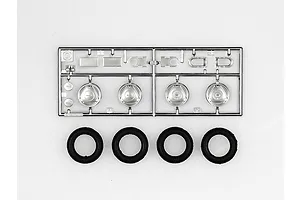 A Tamiya plastic model kit parts sprue featuring chrome-plated wheel components and four separate black rubber tires.