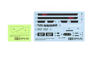 A decal sheet and a masking sticker sheet for the Tamiya 1/24 Mazda Savanna RX-7 model kit, featuring various logos, dashboard gauges, and text labels.