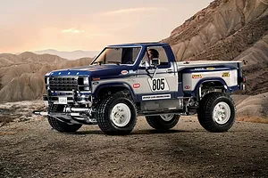 A Tamiya 1/10 scale Ford F-150 Ranger XLT RC truck model parked on a dirt trail with a mountainous desert landscape in the background.