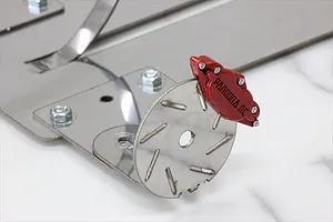 A red Pandora RC brake caliper mounted on a silver metal brake disc, attached to a larger metal mounting plate.