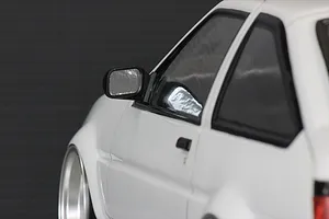 Close-up of a white 1/10 scale RC car body shell featuring a black side door mirror mounted on the driver side door.