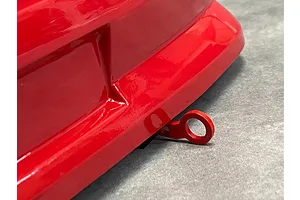 A red RC tow hook mounted to the front bumper of a red RC car body shell.