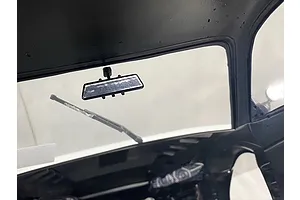 Interior view of an RC car body shell showing a small black rearview mirror mounted to the roof and a windshield wiper.