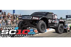 Team Associated Pro2 SC10sw RC short course truck in black jumping over a dirt track with a crowd in the background.