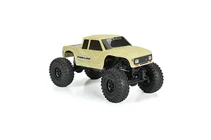 A Pro-Line Coyote RC crawler body shell in tan topographical pattern mounted on a small scale RC chassis against a white background.