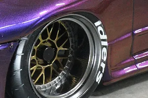 Close-up of a purple RC car wheel featuring a gold mesh rim and a black tyre with white 'idlers' lettering applied to the sidewall.