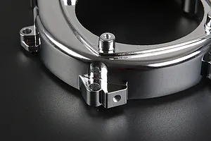 A close-up view of a shiny chrome-finished RC engine cover part against a dark background.