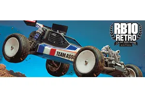 Team Associated RB10 Retro 1/10 scale RC buggy in mid-air action shot against a blue background with dirt flying.