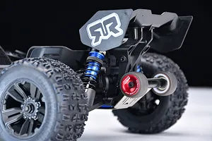 Close-up of a red GPM Racing wheelie bar installed on the rear of an RC truck, featuring aluminium wheel rims and a stainless steel mounting plate.
