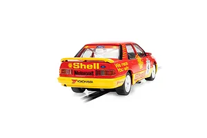 Rear three-quarter view of a red and yellow Scalextric Ford Sapphire RS500 slot car with Shell livery on a track.