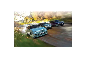 Three Scalextric Ford RS slot cars in light blue, black, and purple driving on a road with motion blur and autumn leaves.