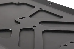 A close-up view of a black anodized aluminium RC main chassis plate with machined cutouts and mounting holes.