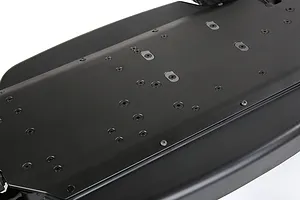 A close-up view of the underside of a black Rovan V5 aluminium RC chassis, showing the flat surface with numerous screw holes and mounting points.