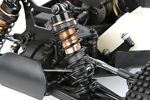 Close-up of a bronze and black adjustable RC shock absorber installed on a remote control vehicle chassis.