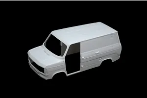 An unpainted white plastic model kit body shell of a Ford Transit van, viewed from a high angle against a black background.