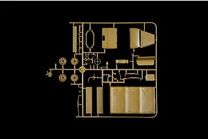 A tan plastic sprue containing various model truck parts, including wheels, a truck bed cover, and interior components, isolated on a black background.