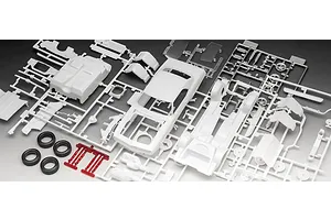 Unassembled plastic model kit parts for a 1969 Chevy Camaro, including white body shells, chrome-plated parts, and black rubber tires on a grey background.