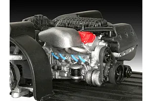 A detailed scale model of a V8 car engine, painted in silver, black, and red, mounted on a black plastic chassis base.