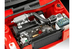 Close-up of a detailed scale model car engine bay, featuring a red chassis, black engine block, and a Varta branded battery.